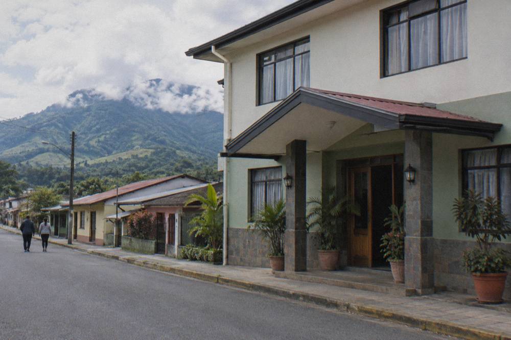 Two-storey town hotel on a quiet Turrialba street with green hills behind the rooftops